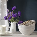 A bouquet of limonium and a set of white dishes: porcelain milk jug, coffee cup, bowls on a white rack on a dark blue background Royalty Free Stock Photo