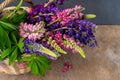 A bouquet of lupines in a basket. Multicolored summer flowers pink and purple on wooden background. Lupine flower buds Royalty Free Stock Photo