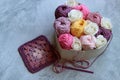 Bouquet of colorful cotton balls in a heart-shaped box on a gray background with copy space. Arts and crafts concept.