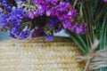 Bouquet of multicolored colors of dry flowers on one-ton background on woven hat made of straw. Violet.