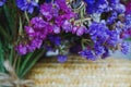 Bouquet of multicolored colors of dry flowers on one-ton background on woven hat made of straw. Violet.