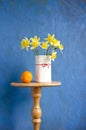 Bouquet narcissus in vase and orange fruit Royalty Free Stock Photo
