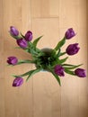 A bouquet of nine purple tulips in a white vase on a wooden background in the center. View from above Royalty Free Stock Photo