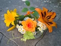 Bouquet of orange lily, rose, daisies, grape leaves, blue clematis on a stone texture