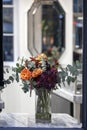 The Bouquet of orange roses, purple dahlias and eucalyptus in a glass vase in front of a mirror Royalty Free Stock Photo