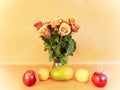 Bouquet of orange roses for the holiday yellow-green avocado two red apples two orange oranges on an orange background Royalty Free Stock Photo