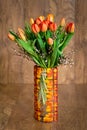 Bouquet of orange tulips in glass colorful vase