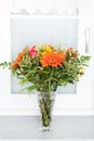 Bouquet of orange, yellow and red flowers in a vase in front of a window. Royalty Free Stock Photo