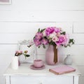 Bouquet of orchids, peonies, roses in a ceramic vase on the bedside table and a stack of books