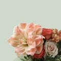 A bouquet of peach daylilies, orange and pink roses and beige chrysanthemums on light green background. Closeup