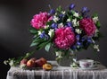 Bouquet of peonies, irises and Jasmine in the jar and the peaches on the table.