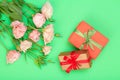 Bouquet of pink flowers with leaves and gift boxes tied with ribbon on green background. Royalty Free Stock Photo