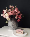 bouquet of pink flowers with a piece of blueberry cake on dark background