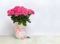 Bouquet pink flowers roses in white porcelain vase and pink hearts on a white table on light background with space for text Royalty Free Stock Photo