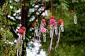 A bouquet of pink flowers in small glass vases hanging in a row on a lamppost in a park. Decorative adornment