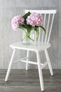 Bouquet of pink hortensia hydrangea flowers in glass vase, standing on white wooden chair Royalty Free Stock Photo