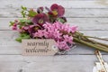 Bouquet with pink hyacinths, Christmas roses and card with text: warmly welcome Royalty Free Stock Photo