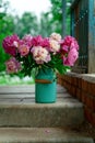 Bouquet of pink peonies in milk can standing on stairs of a country house Royalty Free Stock Photo