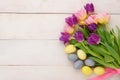 Bouquet of pink and purple tulips and Easter pastel yellow and blue eggs on white wooden background Royalty Free Stock Photo