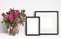 Bouquet of pink rose flowers in a glass vase and brown empty frames on white background Royalty Free Stock Photo