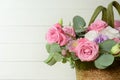 Bouquet of pink roses in basket on white wooden background closeup. Roses and eustoma flowers greeting card, floristics Royalty Free Stock Photo