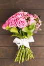 Bouquet of pink roses decorated with white bow of ribbon on wooden background Royalty Free Stock Photo