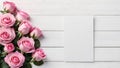 A bouquet of pink roses with green leaves and empty blank for texton white wooden background.