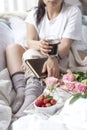 A bouquet of pink roses, in the hands of a girl`s book, Berries of strawberries and fragrant coffee Espresso in the morning. Royalty Free Stock Photo