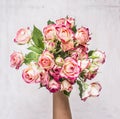 Bouquet of pink shrub roses in the hand of the girl gift on March 8 wooden rustic background top view