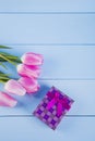 Bouquet of pink tulips with gift box on blue wooden background Royalty Free Stock Photo