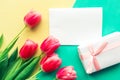 Bouquet of pink tulips and gift box on yellow and green background. Easter or Mother`s Day greeting card. Royalty Free Stock Photo