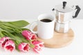 Bouquet of pink tulips, mug and moka pot on a white table. Flat lay with blank copy space Royalty Free Stock Photo