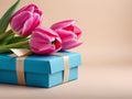 A bouquet of pink tulips next to a blue gift box on a beige background, an empty space for the text on the right