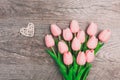 Bouquet of pink tulips and a small white wicker heart on a wooden background Royalty Free Stock Photo