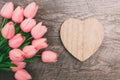 Bouquet of pink tulips and a valentine in the shape of a heart from wood, on a wooden background Royalty Free Stock Photo