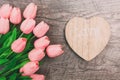 Bouquet of pink tulips and a valentine in the shape of a heart from wood, on a wooden background Royalty Free Stock Photo