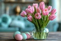 Bouquet of pink tulips in vase on table next to decorated Easter eggs on blurred blue sofa background with daylight Royalty Free Stock Photo