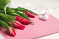 Bouquet of pink tulips with white decorative ribbon on rose lettering paper, selective focus