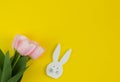 Bouquet of pink tulips and white wooden bunny on a yellow background. Royalty Free Stock Photo