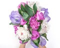 Bouquet of pink and white peonies and irises in woman`s hand isolated on white background. Flat lay