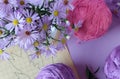 Bouquet of purple chrysanthemums with skeins of multicolored yarn, patterns and knitting needles, pastel background, top view