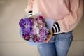 Bouquet of purple fresh flowers in the hands of girl in pink blouse. Royalty Free Stock Photo