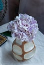 Bouquet of purple in Handmade wooden vase and Vintage fan on white textured table cloth with old cement wall Royalty Free Stock Photo