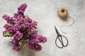 Bouquet of purple lilacs, bonsai scissors and twine on vintage table. Preparation of spring bouquet. Top view.