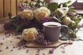 Bouquet of purple lilacs with yellow roses. Gray cup of coffee. Romantic spring flowers.