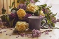 Bouquet of purple lilacs with yellow roses. Gray cup of coffee. Romantic spring flowers.