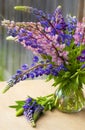 Bouquet of purple lupine flowers in a glass vase table outdoors. Soft selective focus bokeh. Still life with flowers. Lupins. Royalty Free Stock Photo