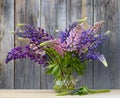 Bouquet of purple lupine flowers in a glass vase table outdoors. Still life with flowers. Lupins. Greeting card for the holiday. Royalty Free Stock Photo