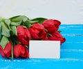 Bouquet of red blooming tulips with green stems and leaves, flowers lie on a blue wooden background Royalty Free Stock Photo