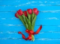 Bouquet of red blooming tulips with green stems and leaves tied with a red silk ribbon Royalty Free Stock Photo